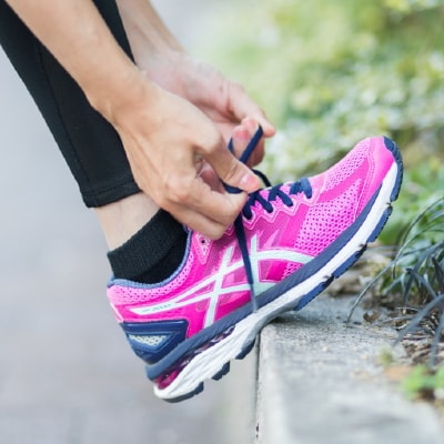 写真：ランニングシューズの紐を結ぶ越迫さんの手元