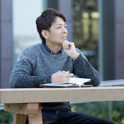 写真：屋外でノートを開く小川さん